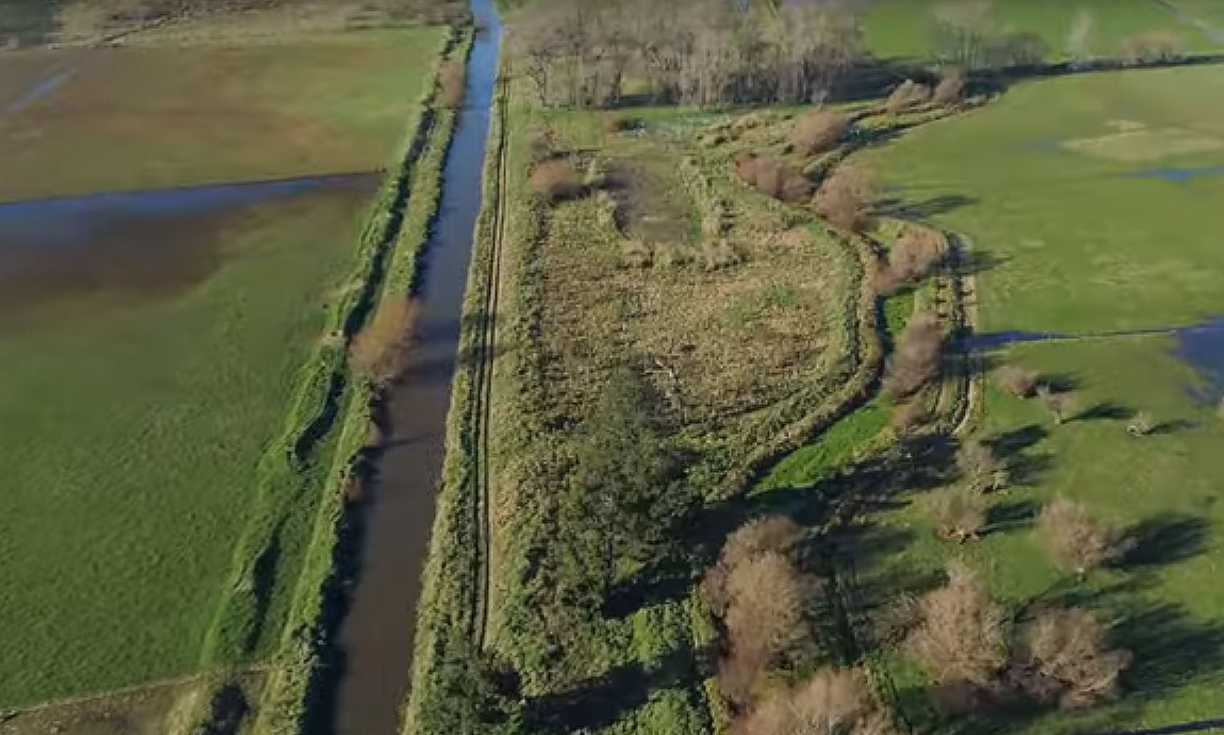 Fig. 1: The current man-made channel of the Hurutini /Haslwelll River (left) and the original natural channel (right). The water visible in the paddocks either side shows how readily this low-lying area is intrinsically wet and poor draining following heavy rains. (Image: ECan/Video 1)